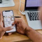 パソコンの前でスマートフォンを操作する手元
