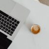 ノートパソコンとコーヒーを置いた白い机