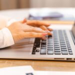 ノートパソコンのキーボードに手を置いて作業する様子
