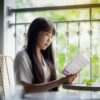 窓辺の椅子で本を読む女性