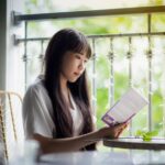 窓辺の椅子で本を読む女性