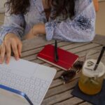 屋外のテーブルでノートを開いて学習する様子