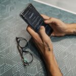 眼鏡を置いた机でスマートフォンを操作する手