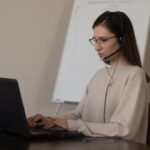 ヘッドセットを着けてノートパソコンに向かう女性