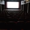 座席が並ぶ誰もいない映画館のスクリーン