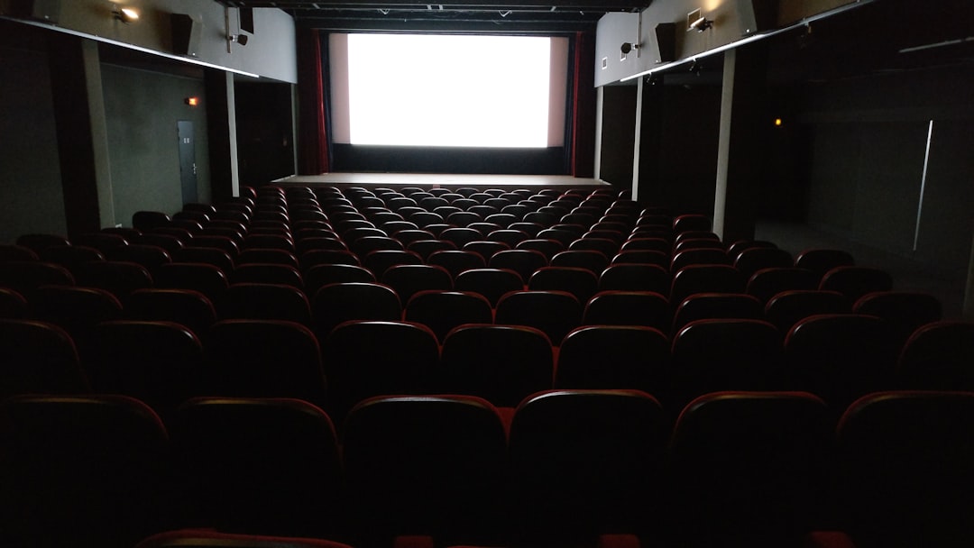 座席が並ぶ誰もいない映画館のスクリーン