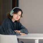 ヘッドホンをつけてテーブルに座る女性