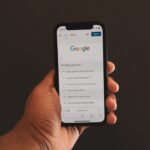 検索画面を表示したスマートフォンを持つ手