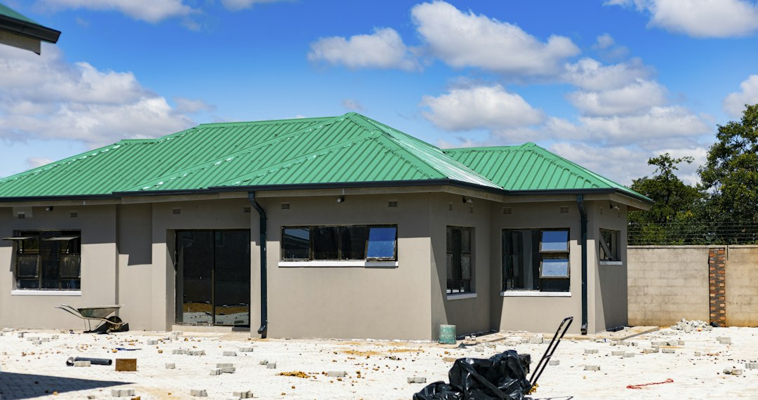 緑色の屋根をした新築住宅と周囲に残る建築中の資材