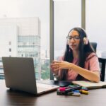 ヘッドホンをつけてノートパソコンでオンライン通話をする女性