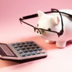 眼鏡をかけた白い貯金箱と机に置かれた電卓