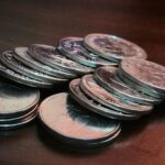 暗い色の机の上に重ねられた複数の硬貨の山