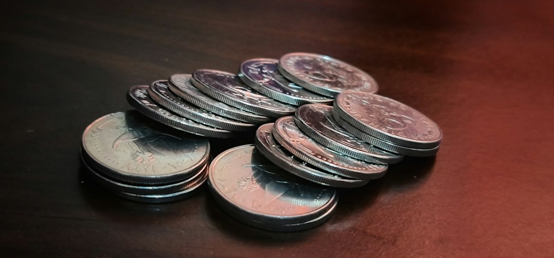暗い色の机の上に重ねられた複数の硬貨の山