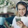 ヘッドホンをつけてソファに座りスマートフォンを操作する女性