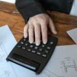 設計図の上で電卓を操作する手