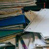 積み重なった書類とファイル、ペン
