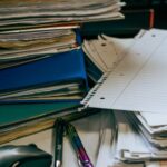 積み重なった書類とファイル、ペン