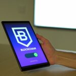 「BLOCKCHAIN」と表示されたタブレット端末を持つ手