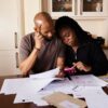 テーブルに広げた書類を確認する黒人の夫婦