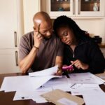 テーブルに広げた書類を確認する黒人の夫婦