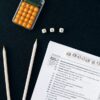黒い背景に置かれたサイコロと申告書類、ペンシル