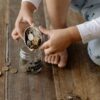 瓶にコインを入れる子どもの手