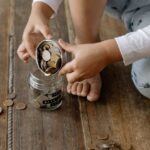 瓶にコインを入れる子どもの手
