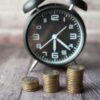 コインの積み重ねの奥に置かれたアラーム時計