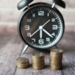 コインの積み重ねの奥に置かれたアラーム時計