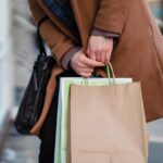 紙袋のショッピングバッグを複数持って歩く人