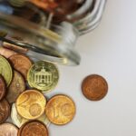 白い机の上でガラス瓶から広がったユーロの硬貨
