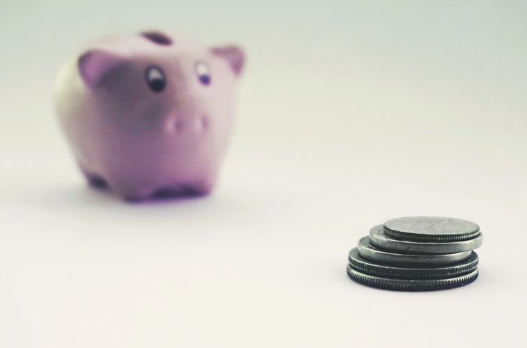 ピンクの貯金箱と積み重なった硬貨