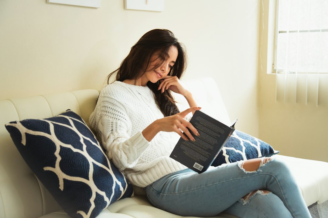 ソファでくつろぎながら本を読む女性