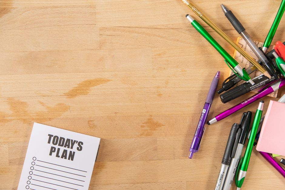 木製デスクに散らばったペンや色鉛筆と「TODAY'S PLAN」のメモ用紙