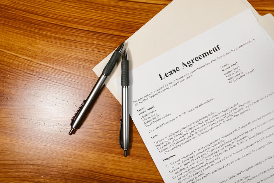 木製デスクに置かれたLease Agreementの書類とペン2本