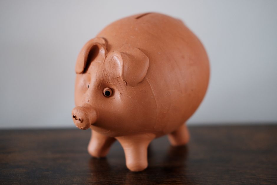 木の台の上に置かれたテラコッタ色の豚の貯金箱