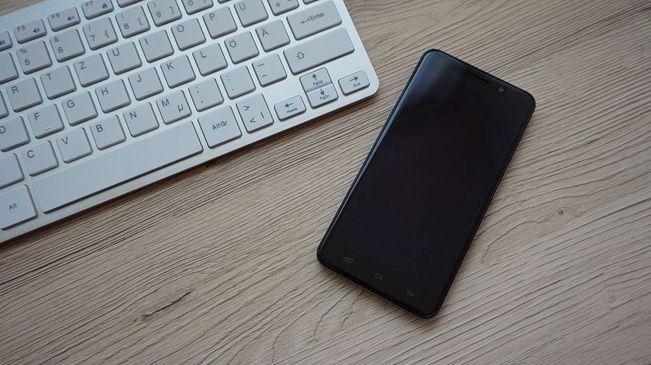 木の机に置かれたスマートフォンとキーボード