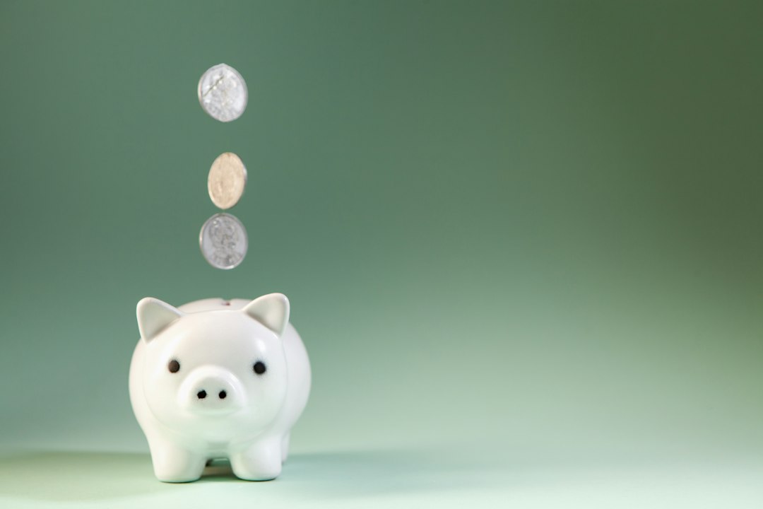 緑の背景の貯金箱に硬貨が落ちてくる様子