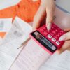 ピンクの電卓でレシートを計算する手元