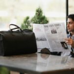 スーツ姿の男性がカフェで新聞を読む様子