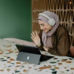ヘッドホンをつけてタブレット端末に向かって手を振る女性