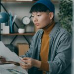 ニット帽をかぶった男性がデスクでノートパソコンに向かう様子