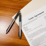 木製デスクに置かれた「Lease Agreement」と書かれた契約書とペン