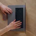 デスクの上でノートパソコンを操作しながら書類を確認する手元