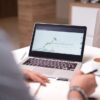 ノートパソコンの画面に表示された取引明細を確認している手元