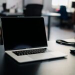 在宅のデスクでノートパソコンの証券会社サイトを操作する手元