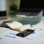 ノートパソコンと手帳、グラフ資料が置かれたテーブル