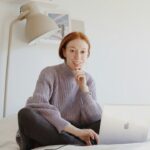 自宅でノートパソコンを開き考え込む女性